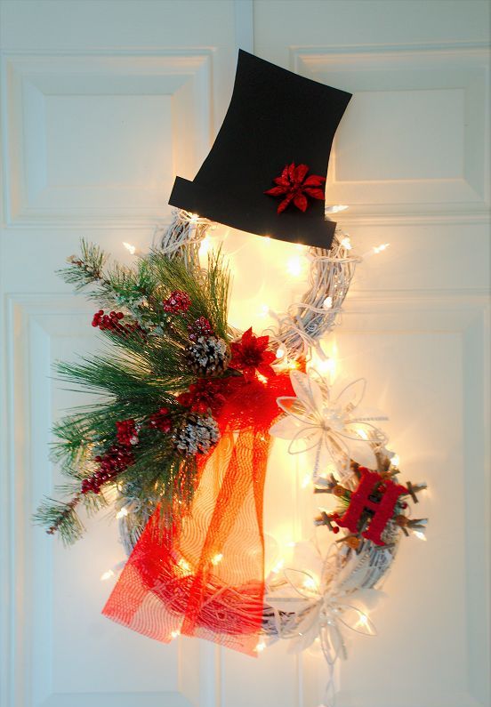 a pretty lit up Christmas snowman of whte vine wreaths, evergreens, berries, a top hat and a monogram is a lovely solution