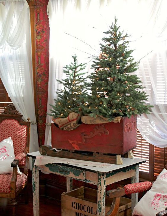 a red box sleigh with Christmas trees with lights and burlap is amazing for rustic holiday decor with a vintage feel