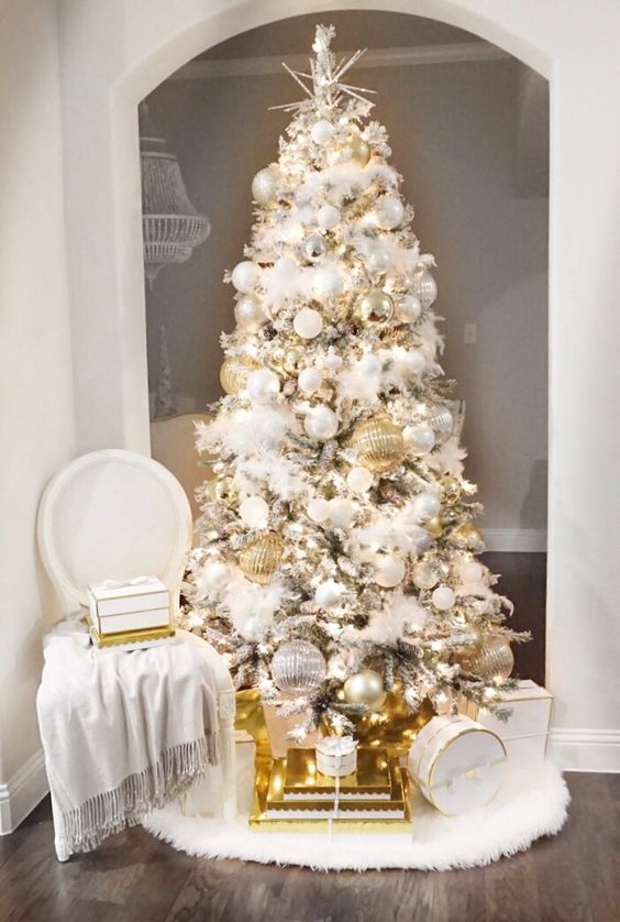 a refined and glam Christmas tree with white and silver plus oversized gold ornaments, lights and a star topper