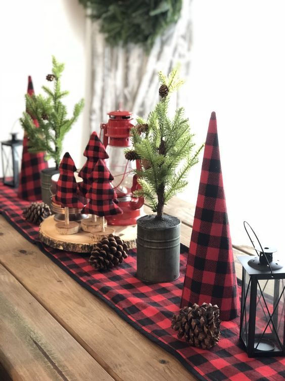a rustic Christmas tablescape with a red plaid runner and matching fabric trees, potted Christmas trees with pinecones and wood slices