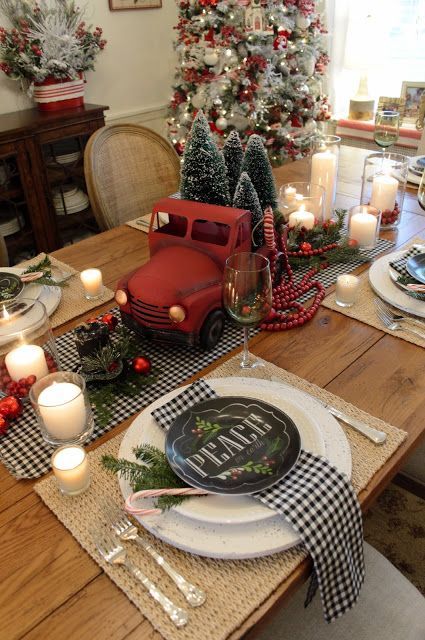 طاولة ريترو ريترو لعيد الميلاد مع عداء مربعات جاموس ومناديل ، ومفارش منسوجة ، وشاحنة حمراء مع فرشاة زجاجة ، أشجار عيد الميلاد والشموع