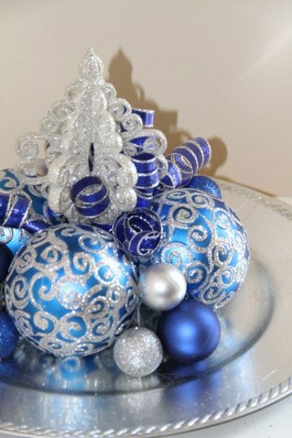 a simple Christmas centerpiece of a silver plate, silver, silver glitter and blue ornaments is a stylish and bright decoration