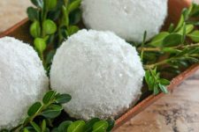 a simple centerpiece of a wooden tray with greenery and shiny snowballs can be easily made last minute and looks cool