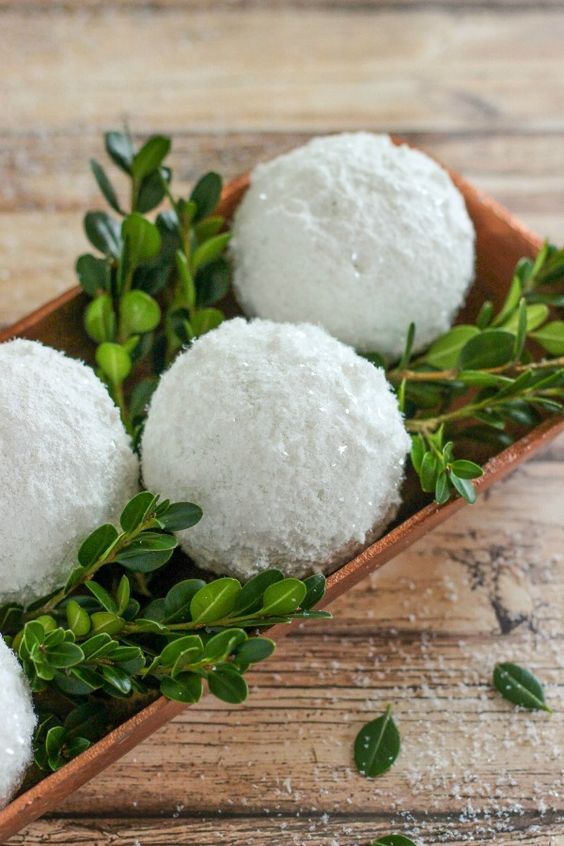 a simple centerpiece of a wooden tray with greenery and shiny snowballs can be easily made last minute and looks cool