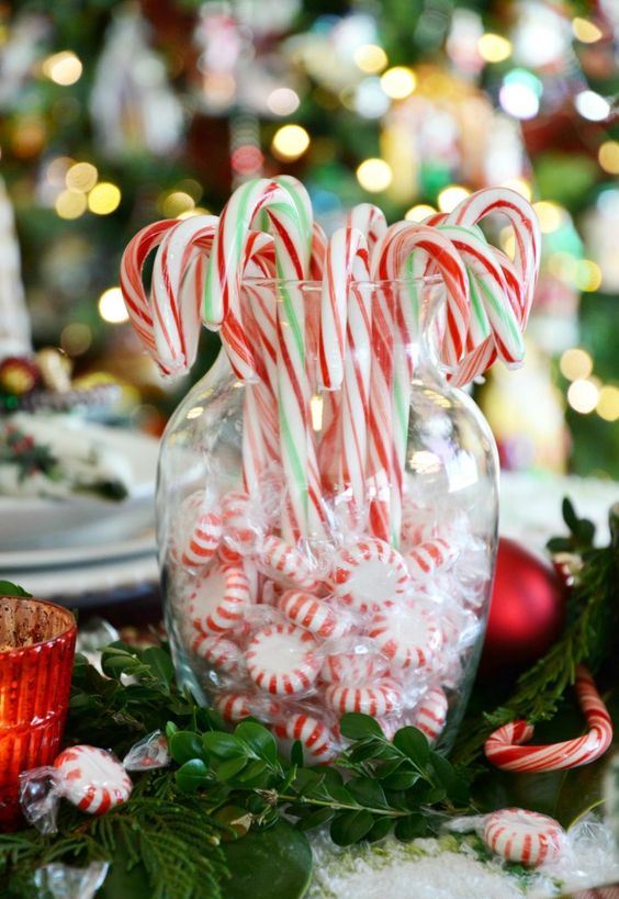 a simple edible decoration of a vase with peppermints and candy canes and greenery around is a stylish idea for holiday decor