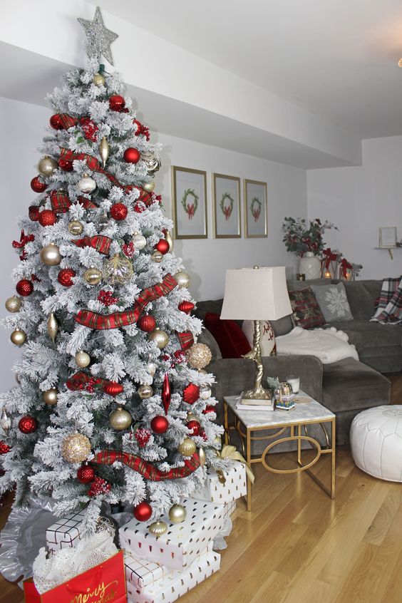 a snowy Christmas tree with gold and red ornaments, plaid ribbons and a silver tree topper