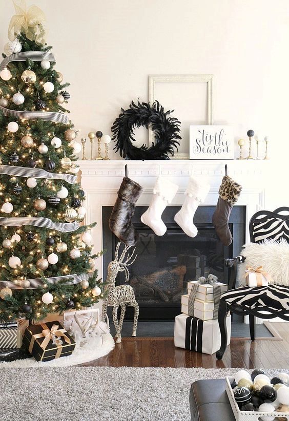 a stylish black, gold and white Christmas tree with lights, striped ribbons and a tulle bow on top is lovely