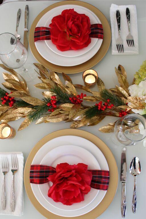 a stylish red and gold Christmas table with gold foliage, evergreens and berries, red blooms and candles