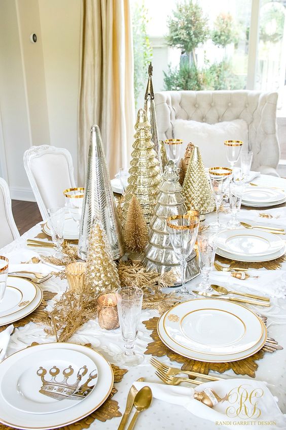 a super chic and elegant gold and white Christmas table setting with gold, silver cone Christmas trees, gold sunburst chargers and cutlery