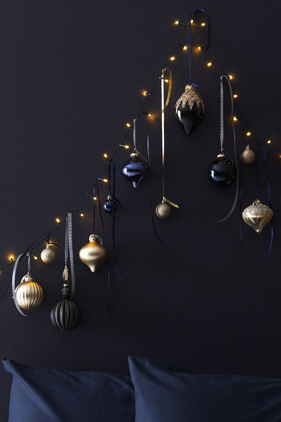 a unique Christmas tree of lights and black, navy and gold ornaments hanging on them is a lovely space-saving idea