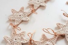 a white knit star garland with twine is a pretty idea to style a Christmas tree, a mantel, a window or you may use them as gift tags