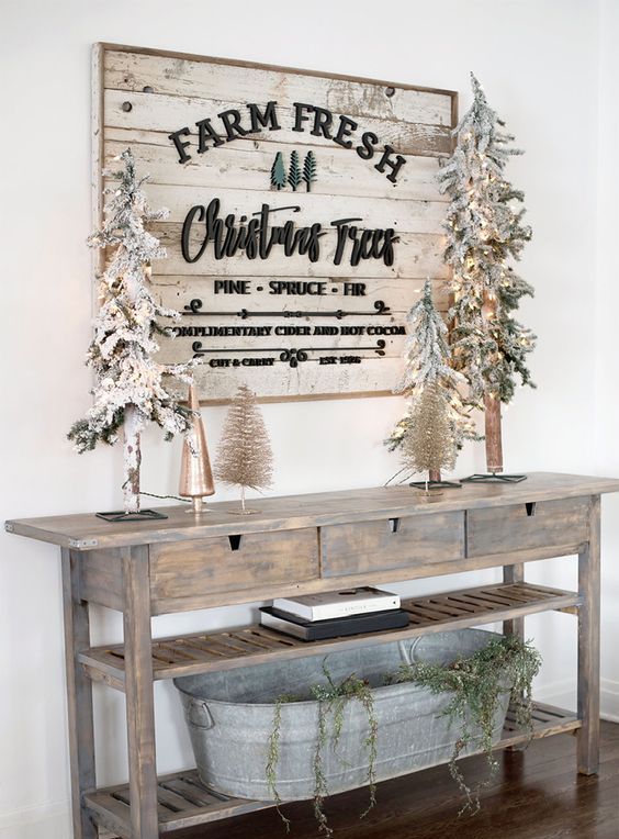 a whitewashed farmhouse Christmas sign with black letters and calligraphy, green wooden Christmas trees attached