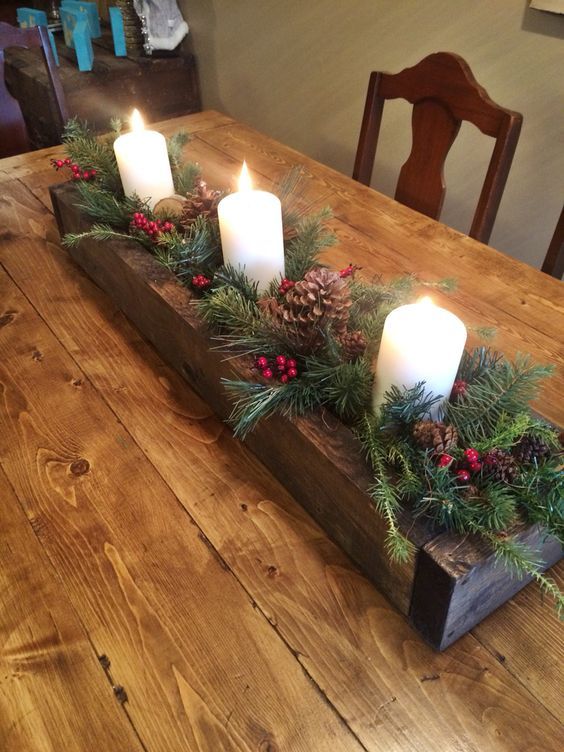 a wooden planter with evergreens, pinecones, berries and pillar candles is a lovely rustic Christmas centerpiece or decoration