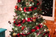 an amazing woodland Christmas tree with a red plaid ribbon, snowy pinecones, lights and red and gold glitter ornaments