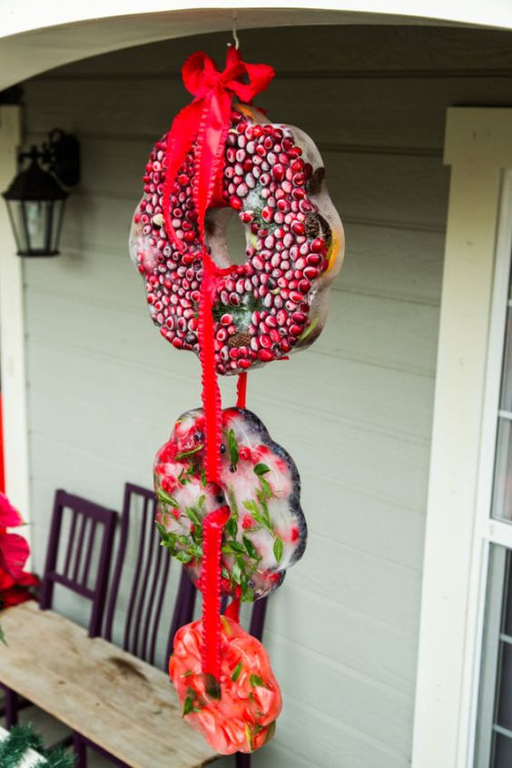 an arrangement of ice Christmas wreaths with cranberries, greenery and various fruit is a very cool idea for outdoors
