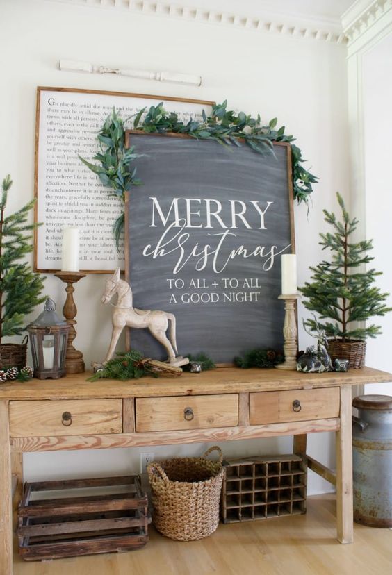 an awesome chalkboard Christmas sign decorated with greeneyr on top is a stylish farmhouse holiday decor idea