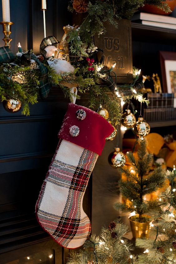 an exquisite and glam Christmas mantel with an evergreen and plaid garland, a plaid stocking with Christmas ornaments