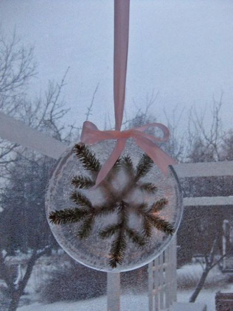 an ice Christmas decoration with evergreens inside paired with a pink ribbon bow is a lovely idea for a rustic space