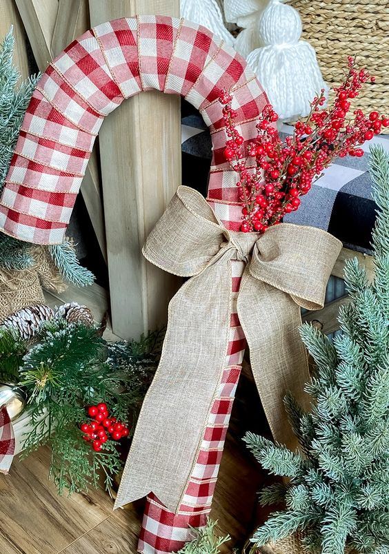 an oversized plaid candy cane wreath with a burlap bow and some berry branches is a lovely and bold decoration for outdoors and not only