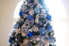 bold Christmas tree decor with silver, blue and navy ornaments, fabric blooms and a star topper is a cool idea for holidays
