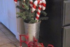 classy Christmas decor with a bucket with fir branches, candy canes and letters is gorgeous and whimsical
