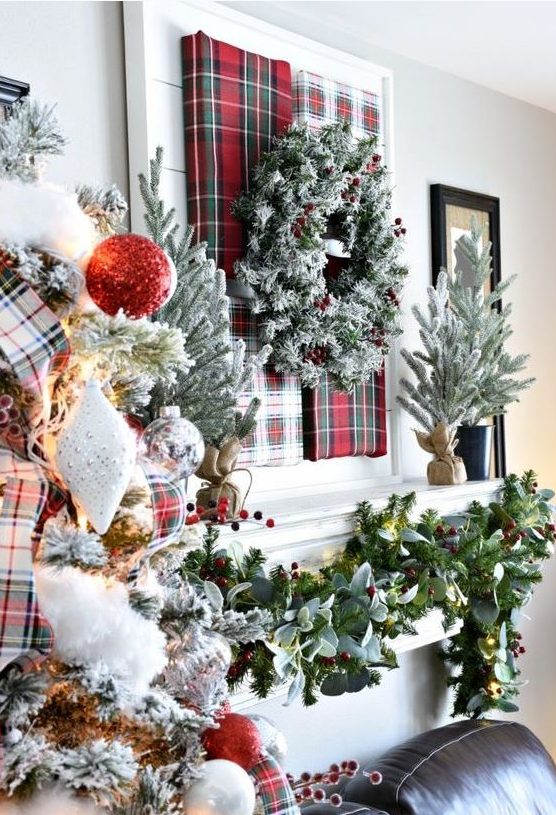 lush Christmas decor with a plaid art and a snowy wreath,, a greenery and berry garland, a flocked Christmas tree with red gltter and silver ornaments