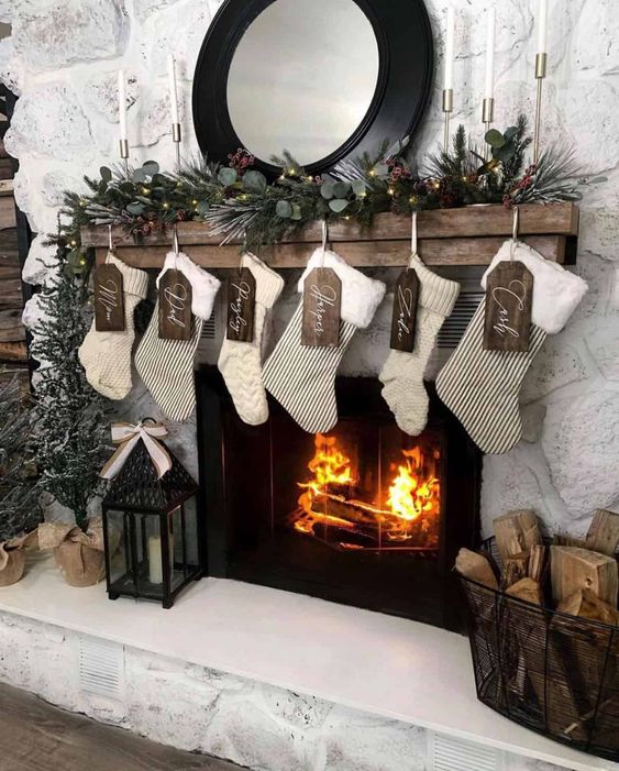 neutral crochet and striped stockings with plywood tags, an evergreen garland with lights and pinecones for Christmas