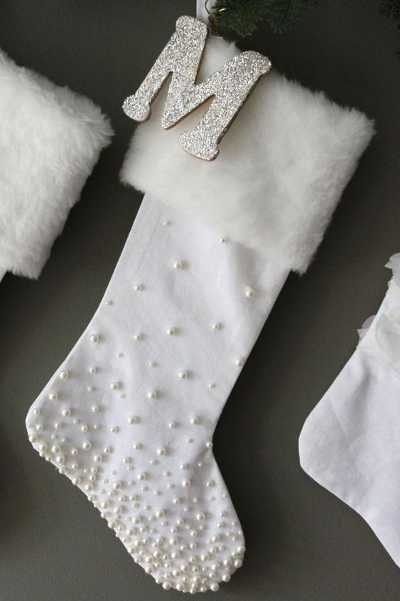 refined white stockings with pearls and white faux fur plus glitter monograms are super refined and chic Christmas decorations