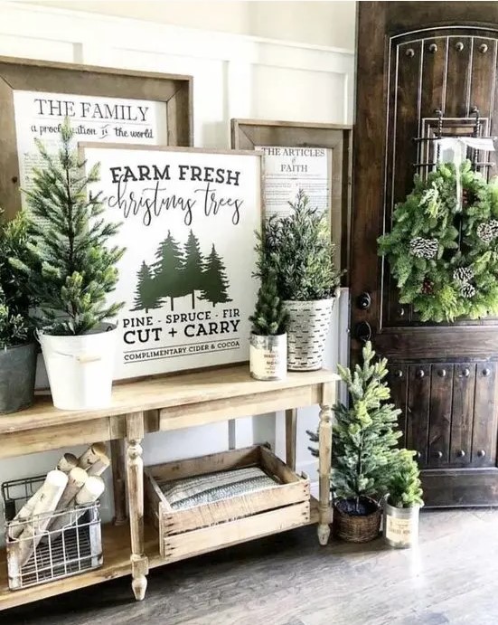 rustic Christmas entryway decor with lots of Christmas trees in buckets, vintage Christmas signs, crates and baskets with firewood