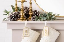 white and gold embroidery stockings, greenery, snowy pinecones and gilded candleholders with pilalr candles for Christmas decor