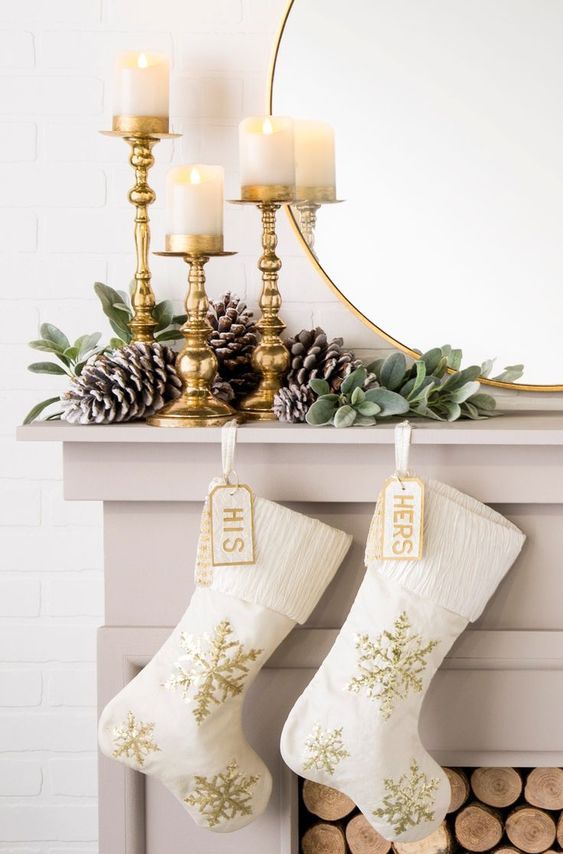 white and gold embroidery stockings, greenery, snowy pinecones and gilded candleholders with pilalr candles for Christmas decor