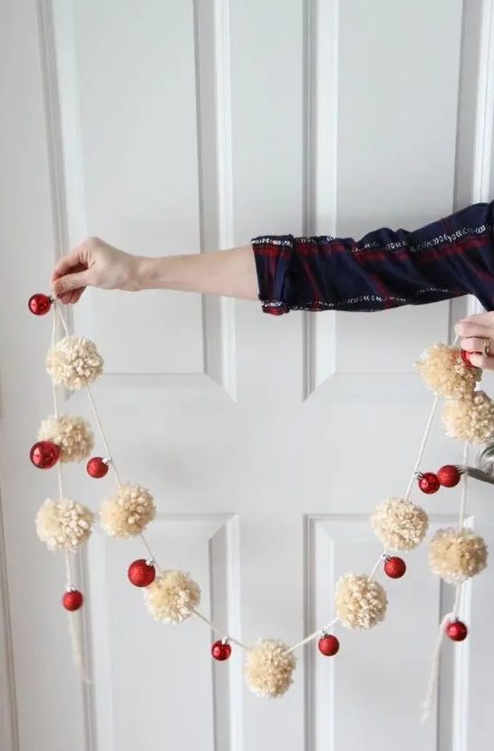 a Christmas garland of neutral pompoms and red ornaments is a truly holiday decoration to rock