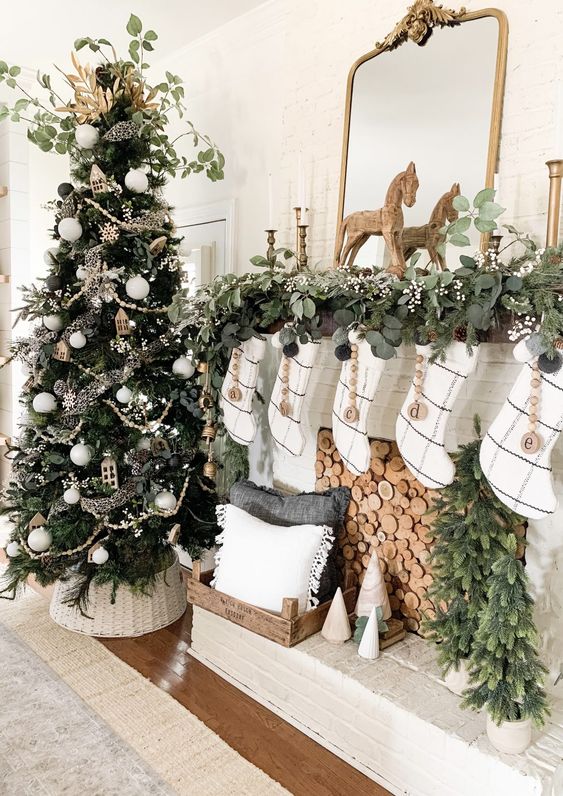 a beautiful all-natural Christmas tree with white ornaments, plywood houses and snowflakes and lush fresh greenery for a topper