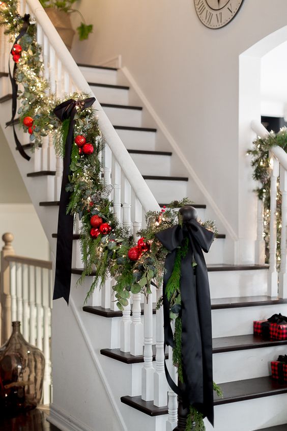 a beautiful holiday garland of evergreens and greenery, red ornaments, lights and large black ribbon bows is pure elegance