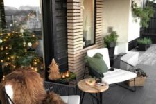 a contemporary winter terrace with black metal furniture, a hairpin leg table, a fire bowl and faux fur plus candles and a small tree