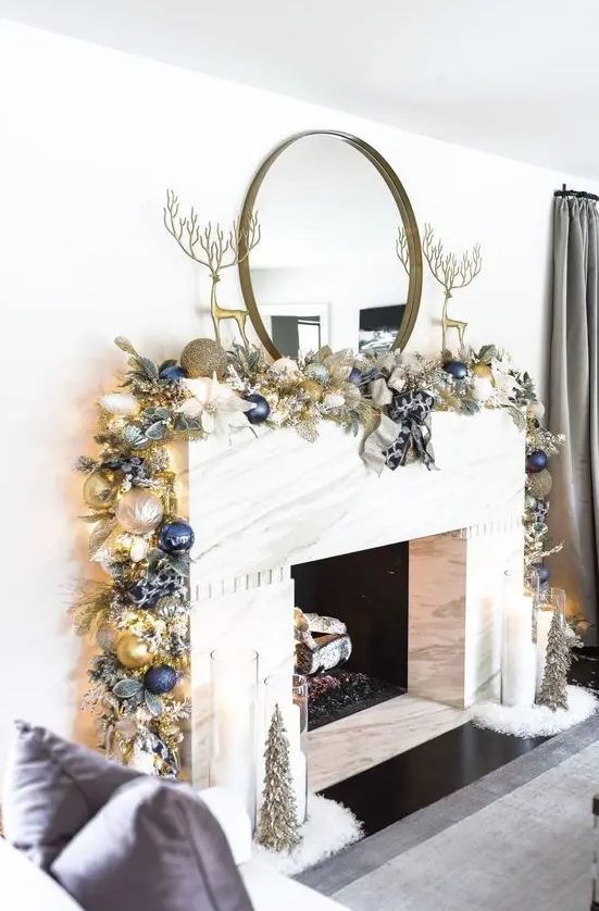 a glam Christmas mantel with a gold, silver and navy Christmas ornament garland and tall gold deer figurines is a chic idea to rock