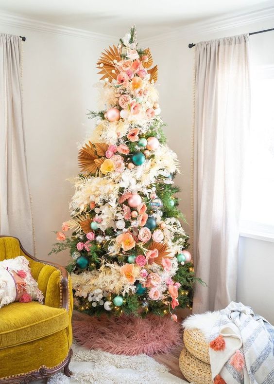 a gorgeous tropical Christmas tree with pink, blue and green ornamnets, blooms, greenery and with fronds as tree toppers is wow