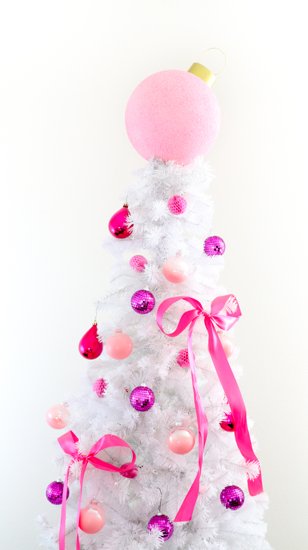 a gorgeous white Christmas tree decorated with bubblegum pink, fuchsia and purple ornaments and ribbons and topped with an oversized Christmas ornament in pink