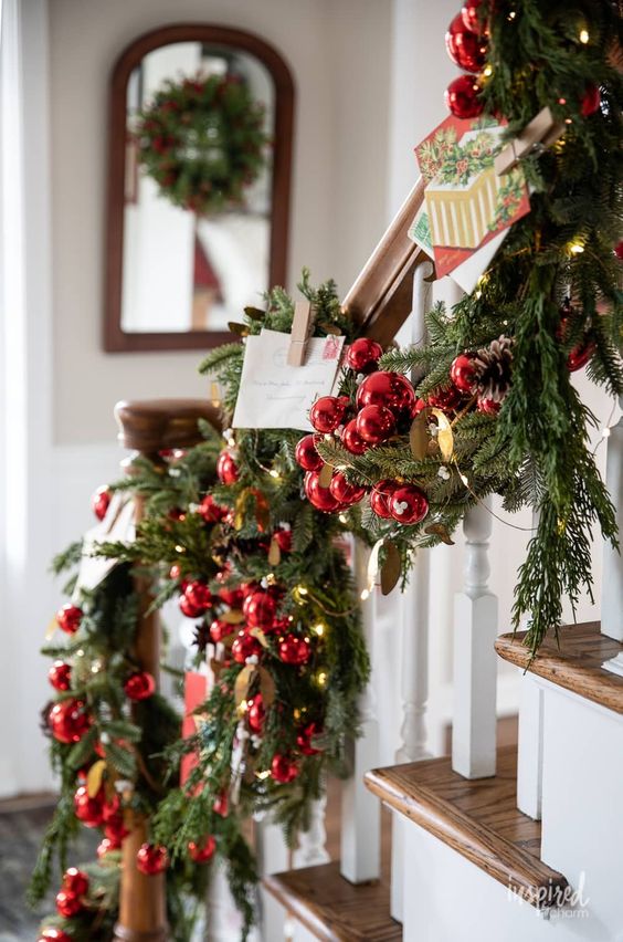a lovely and bright Christmas garland of evergreens, lights, pinecones and red ornaments plus some vintage postcards is cool