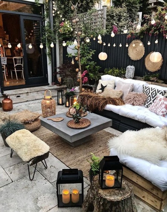 a lovely winter terrace with a black wooden bench and a stained loveseat, a concrete coffee table, a metal stool, candle lanterns and lights is cool