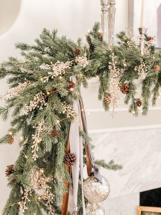 a lush Christmas garland of evergreens, pinecones, lights and dried branches plus some mercury glass ornaments for a mantel