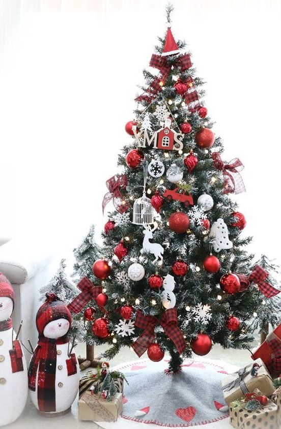 a pretty and bright white and red Christmas tree with snowflakes, cages, houses, snowmen, deer and an elf hat Christmas tree topper