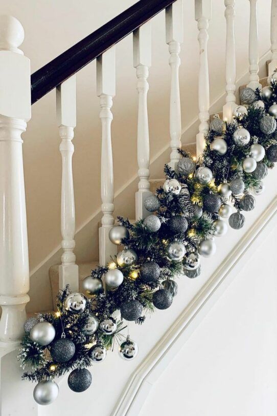 a pretty and shiny Christmas garland of evergreens, silver and grey ornaments and lights is perfect for styling your space for the holidays