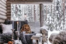 a roofed winter terrace of wood, with grey textiles and grey faux fur, candle lanterns and candles is a lovely space