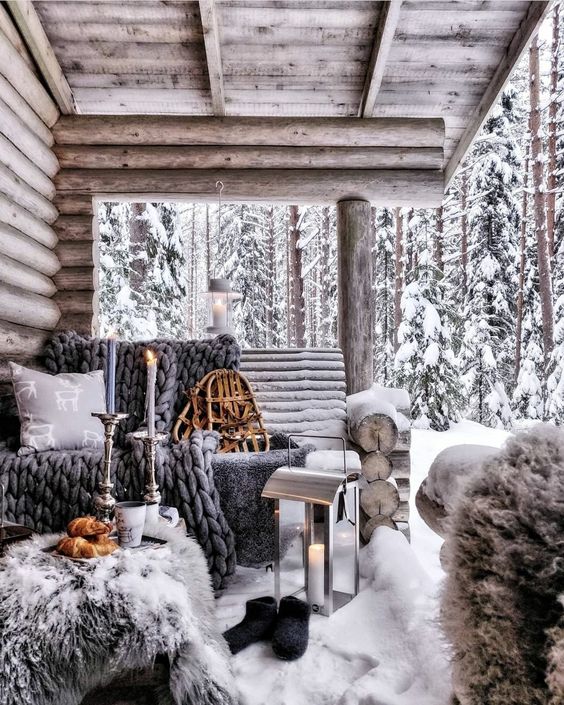 a roofed winter terrace of wood, with grey textiles and grey faux fur, candle lanterns and candles is a lovely space