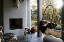 a roofed winter terrace with a fireplace, a woven pendant chair and woven chairs, faux fur and a grey pouf