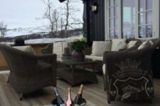 a simple and cozy winter terrace with wicker furniture, neutral upholstery and pillows, faux fur rugs and a bowl with bottles