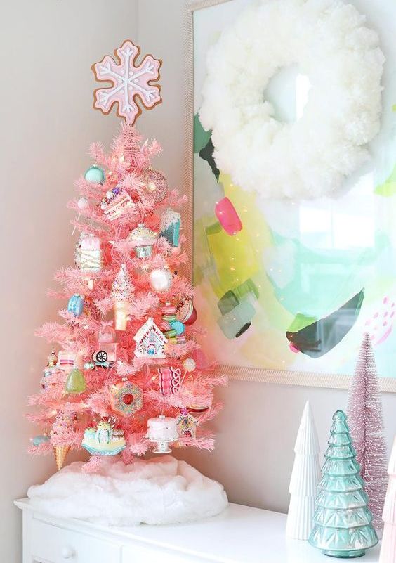 a super fun and bright pink Christmas tree with donut, house, ice cream and usual ornaments topped with a gingerbread snowflake cookie for more fun