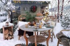 a winter patio done with vintage wooden furniture, evergreens, candle lanterns and firewood storage is a cool and cozy space
