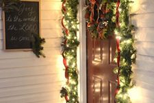 an evergreen and light garland with a red ribbon and a matching wreath will make your front porch look Christmassy
